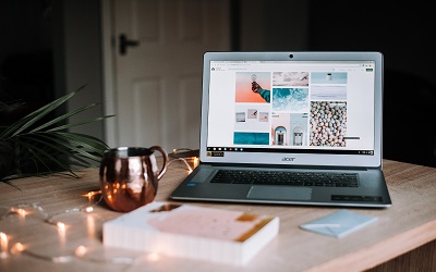 Image by Anete Lusina on Unsplash. Photo shows a laptop on a table with a gold coffee cup in front of it and a green plant to the left