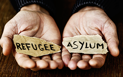 Hands holding papers saying refugee and asylum