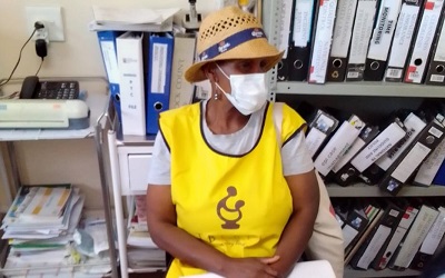 SDI Federation ‘Mamas’ lead with youth members of the alliance to bring people from informal settlements to vaccination stations nearby to be vaccinated. This 'mama' is pictured in a hat and mask and yellow vest