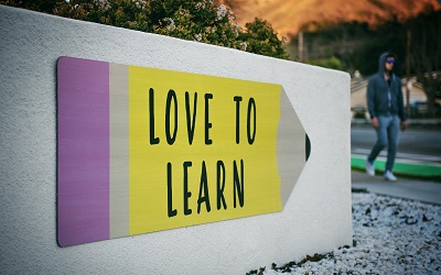 'Love to Learn' is shown on a bright, large sign shaped like a pencil
