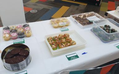 An array of cakes, including cupcakes, cookies and doughnuts, displayed on a table top.