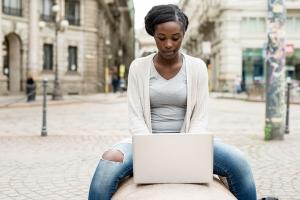 Image of a woman sitting on a bench using a laptop 