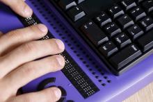Fingers typing on a braille display keyboard