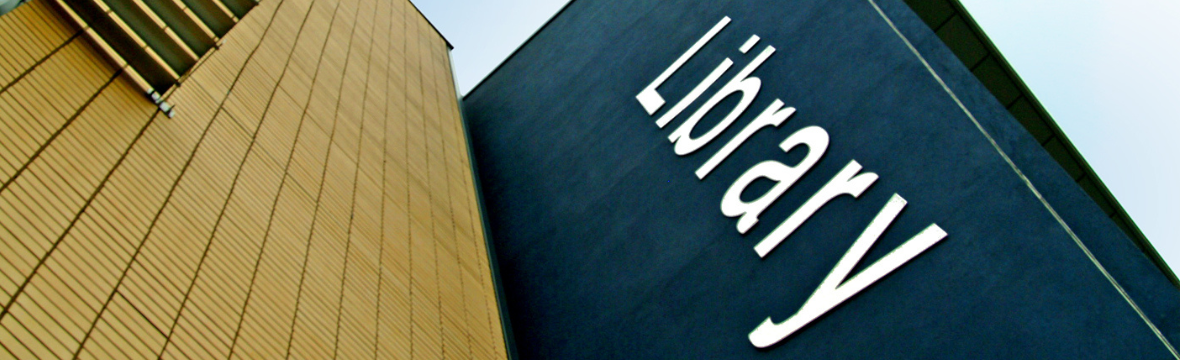 A brown building next to a nave blue building featuring a large sign saying 'Library'