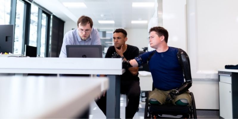 Three men looking at a laptop on a desk