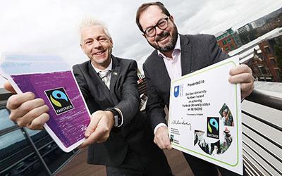 two men holding pages with a fairtrade logo and a certificate