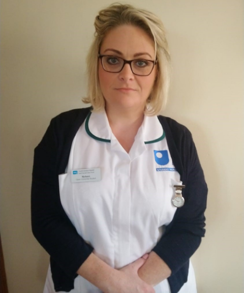 A picture of Noleen stood against a plain wall in her OU student nurse uniform