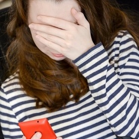 girl with mobile phone and hand covering face