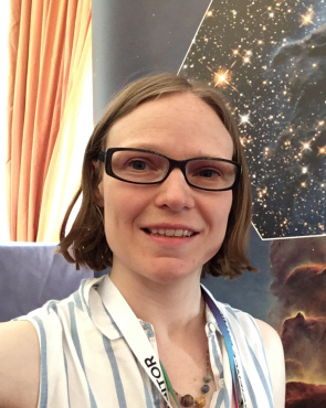 A woman, smiling, standing in front of an image of the Pillars of Creation 