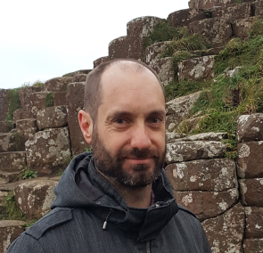 A picture of Matt Balme in front of some basalt columns 