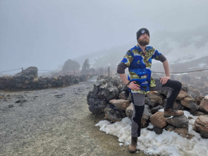 Picutre of Adam standing on top of a volcano, surrounded by snow. He looks very proud of himself as he should be
