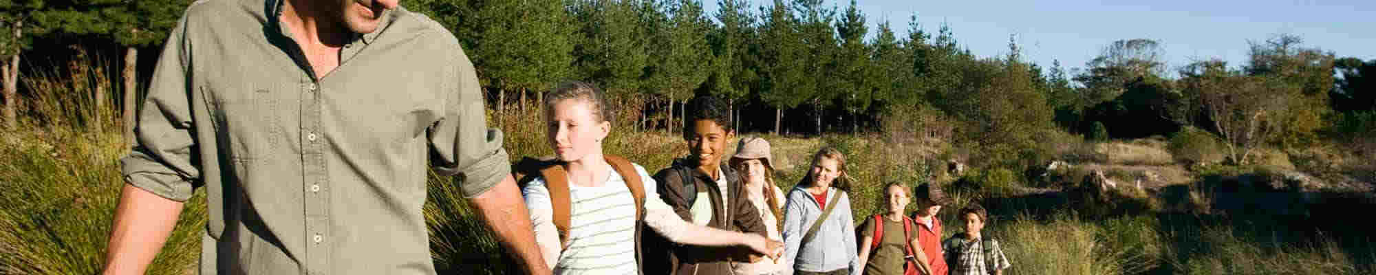 a line of children led by an adult walking hand in hand