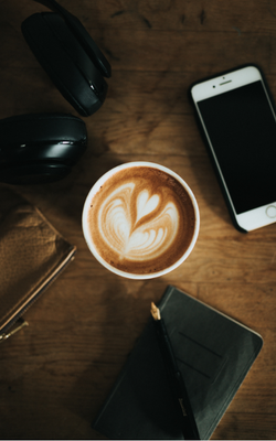 Photo of a cup of coffee and a smart phone on a table, by Nathan Dumlao on Unsplash.
