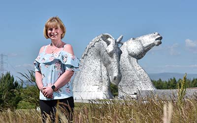 OU graduate Emma, standing with the Kelpies in the background