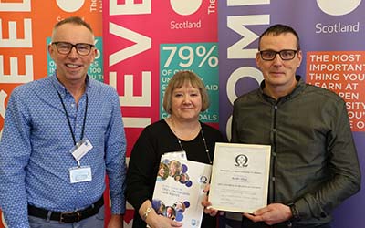 Keith pictured holding his certificate at the Association of OU Graduates awards