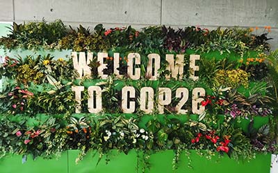 Letters spelling out 'Welcome to COP26', surrounded by plants