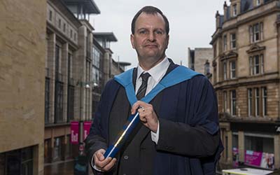 OU graduate Scott outside the Glasgow Royal Concert Hall on graduation day