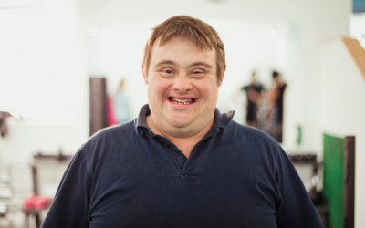 A man with Down's syndrome, who is facing directly to the camera and smiling.