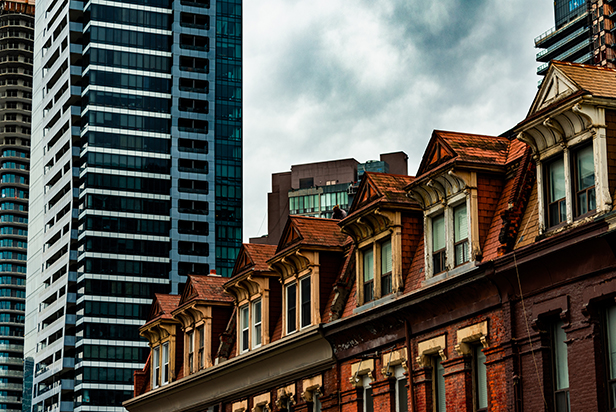 The tops of old brick buildings surrounded by skyscrapersin downtown Toronto