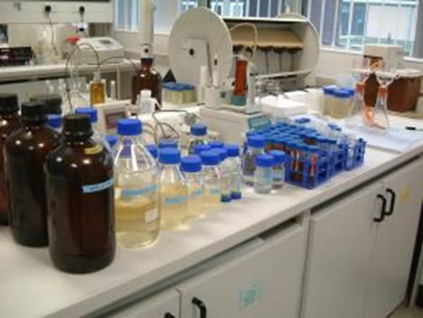 A lab with chemicals in different sizes bottles on a bench