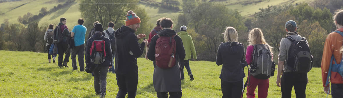 Large group in outdoor clothing walking away from the camera across a field.