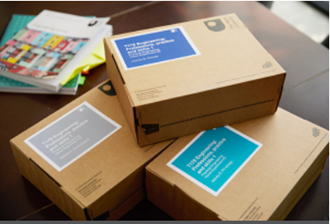 This is a photo of three boxes of printed Open University materials. Several Open University books are on the table in the background.