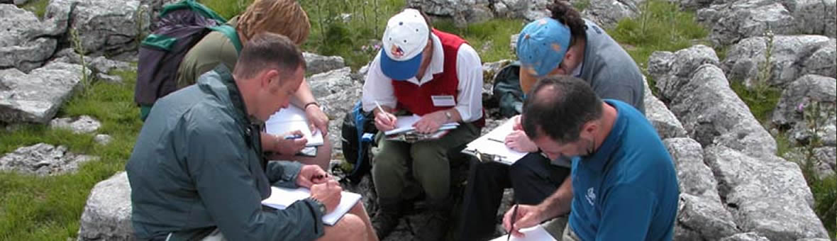Student Support - a group of field school students writing notes while sitting on rocks.