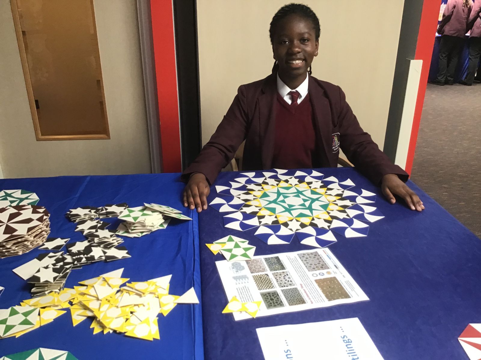 A young person sits behind a table of tiles
