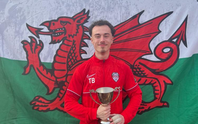 A picture of Tomos in football kit in front of a Welsh flag